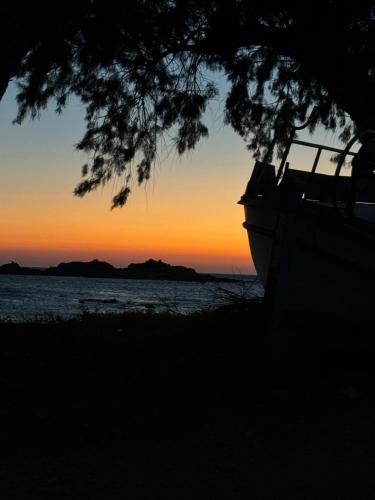 a boat sitting on the beach at sunset at Baloma Studio in Áyios Fótios