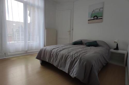 Un dormitorio con una cama en una habitación blanca. en Escapade en bord de mer, en Dunkerque