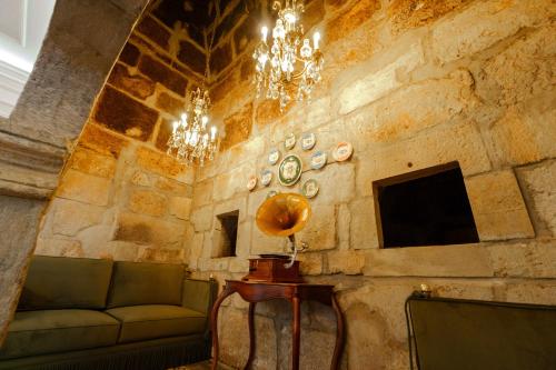 a room with a stone wall with a couch and chandelier at Boutique Hotel Teatro in Angra do Heroísmo