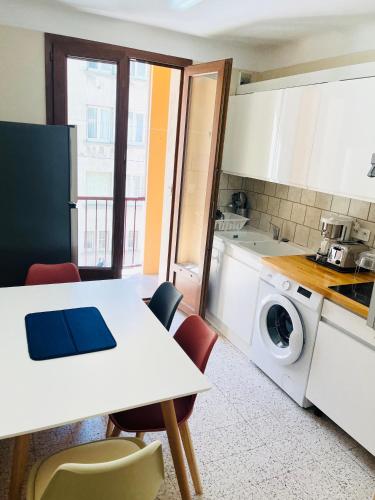 une cuisine avec une table et une machine à laver dans l'établissement Au Pied Des Remparts, à Avignon