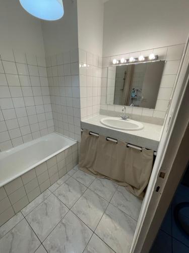 une salle de bain avec un lavabo, une baignoire et un miroir dans l'établissement Le Beau Repaire de Jean, à Beaurepaire