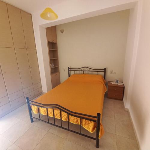 a bedroom with a bed with an orange bedspread at Central Rooms in Makry Gialos