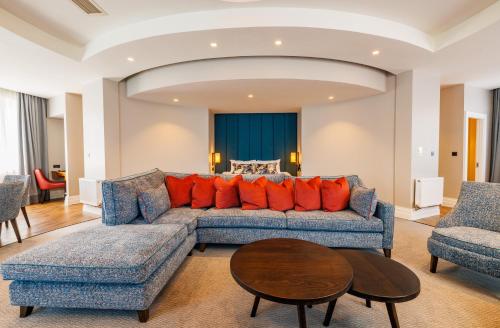 a living room with a blue couch and orange pillows at Mount Wolseley Hotel Spa & Golf Resort in Tullow