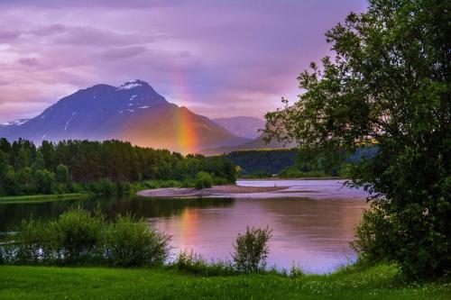 a rainbow over a river with a mountain at Målselv Fjellandsby Apartments in Bardufoss