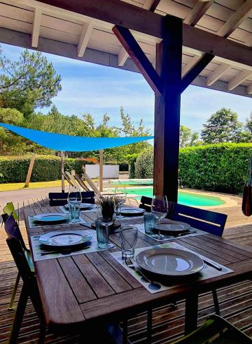 - une table en bois avec des assiettes et des verres à vin sur la terrasse dans l'établissement Villa Messangeles, à Messanges