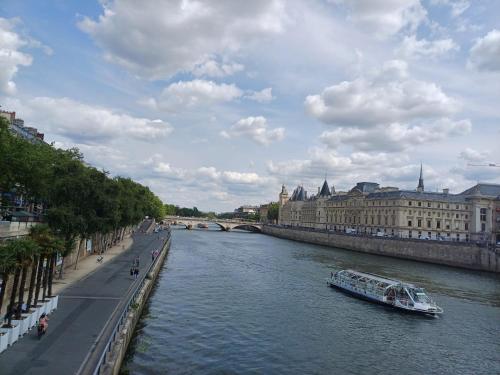 a boat traveling down a river in a city at Happy Stay Paris - Suite Hotel de Ville le Marais in Paris