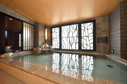 a large swimming pool in a building with a large window at Dormy Inn Higashi Muroran in Muroran