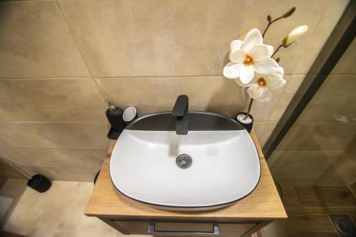 a white sink on a wooden table with flowers at Apartmani Monero in Vrnjačka Banja