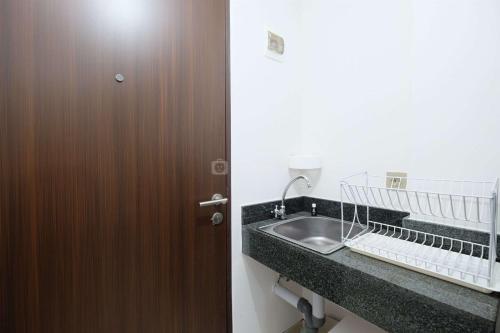 baño con lavabo y puerta marrón en Simply Look Studio at Transpark Cibubur Apartment By Travelio, en Depok