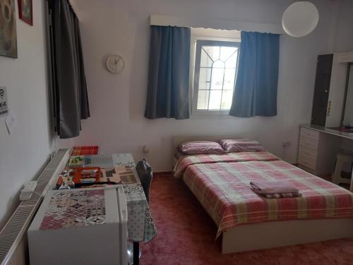 a bedroom with two beds and a desk and a window at Vasilis house in Mor Menekshe
