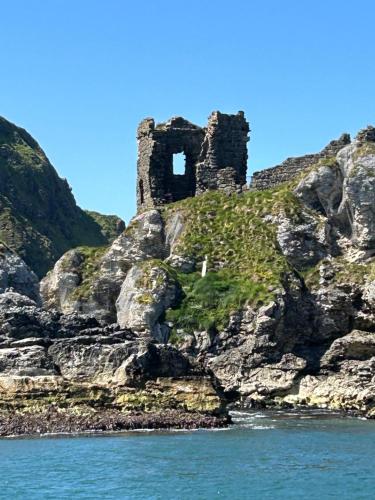 an old castle on a rocky island in the water at Bayview Farm Holiday Cottages in Bushmills