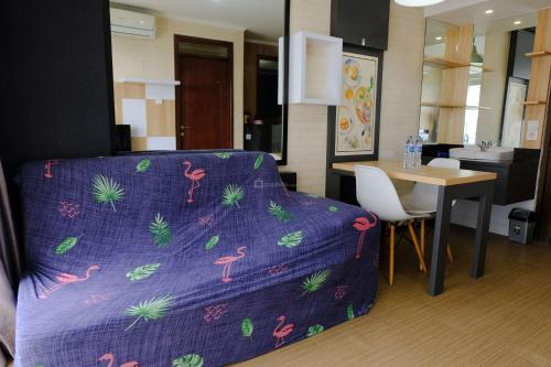 a living room with a purple bed and a table at Strategic and Comfortable 2BR Apartement at Gateway Pasteur By Travelio in Bandung