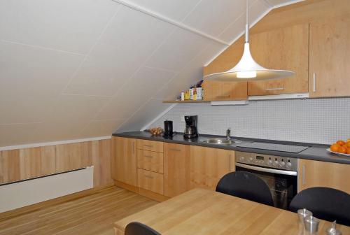 an attic kitchen with wooden cabinets and a table at Vossestrand Hotel and Apartments in Myrkdalen 