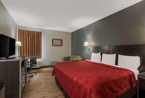 a hotel room with a red bed and a television at Econo Lodge Inn & Suites Diamondhead in Diamondhead