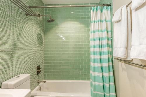 a green tiled bathroom with a tub and a toilet at Snowcreek V 731 in Mammoth Lakes