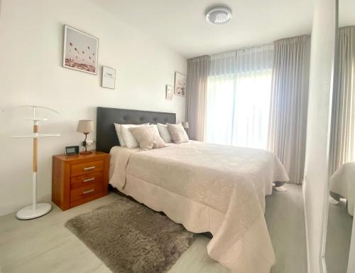 a white bedroom with a bed and a window at Fin Albir Playa in Albir