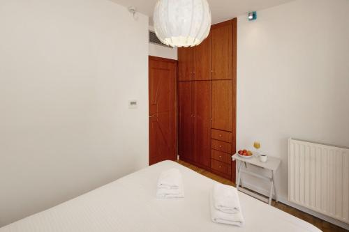a white room with a bed and a chandelier at Holiday Maisonette in Varkiza by GHH in Vari