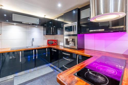 a kitchen with black and purple cabinets and a sink at Casa 42 - Cozy & Fancy Boutique House in Barão de São João