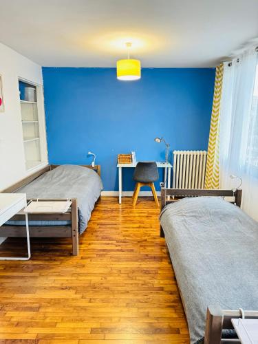une chambre avec deux lits et un mur bleu dans l'établissement Chambres privées proche de Versailles, à Fontenay-le-Fleury