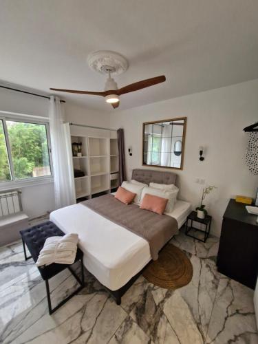 une chambre avec un grand lit et un ventilateur de plafond dans l'établissement T2 neuf centre ville Saint Raphaël avec terrasse et parking gratuit, prés de la plage et commerces!, à Saint-Raphaël