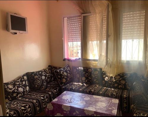a living room with a couch and two windows at Adorable Apartamento a 8 Min del Aeropuerto de Casablanca,WiFi Ultra Rapido y Parking Gratis in Derroua
