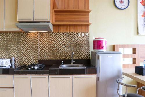 a kitchen with a stove and a sink in it at Spacious Studio The Edge Bandung Apartment By Travelio in Bandung