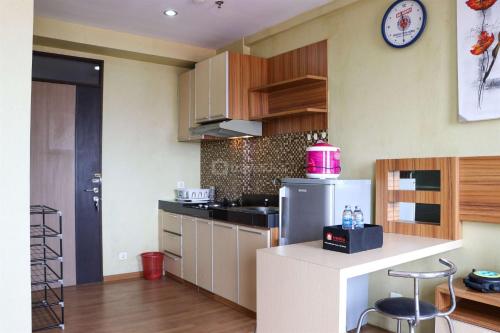 a kitchen with a white refrigerator and a clock on the wall at Spacious Studio The Edge Bandung Apartment By Travelio in Bandung