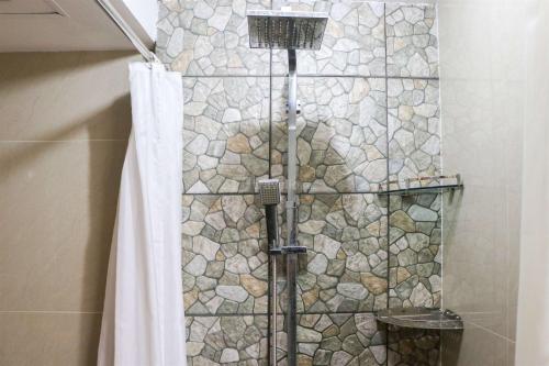 a shower with a stone wall in a bathroom at Spacious Studio The Edge Bandung Apartment By Travelio in Bandung