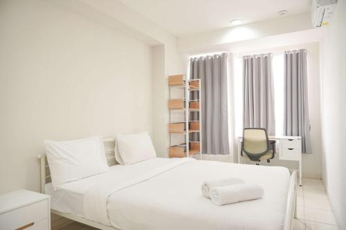 ein weißes Schlafzimmer mit einem weißen Bett und einem Stuhl in der Unterkunft Homey and Minimalist 1BR Cinere Bellevue Suites Apartment By Travelio in Karangtengah