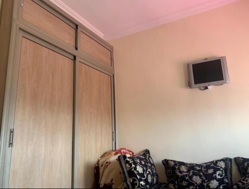 a room with a couch and a tv on the wall at Adorable Apartamento a 8 Min del Aeropuerto de Casablanca,WiFi Ultra Rapido y Parking Gratis in Derroua