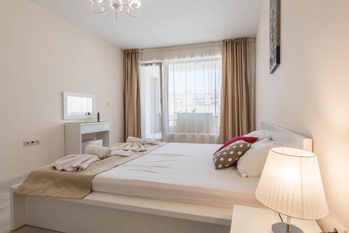 a white bedroom with a large bed with a window at Seaside Apartment in Varna City