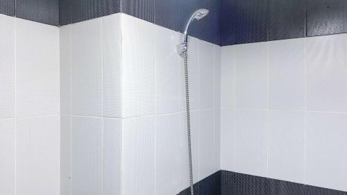 eine Dusche im Bad mit schwarzen und weißen Fliesen in der Unterkunft Homey and Minimalist 1BR Cinere Bellevue Suites Apartment By Travelio in Karangtengah