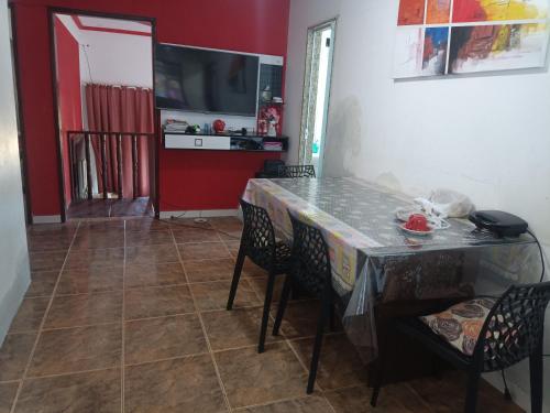a dining room with a table and chairs and a television at Casa primavera in São Pedro da Aldeia