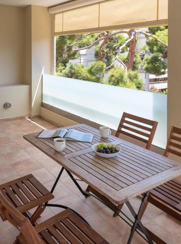 a wooden table with a bowl of fruit and two chairs at Holiday Maisonette in Varkiza by GHH in Vari