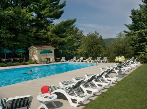a row of lawn chairs next to a swimming pool at The Manor on Golden Pond in Holderness
