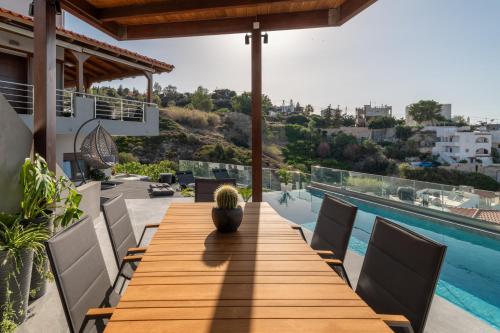 a wooden table on the roof of a house with a swimming pool at D&A View Luxury Villa 60meters from the Sea in Lygaria