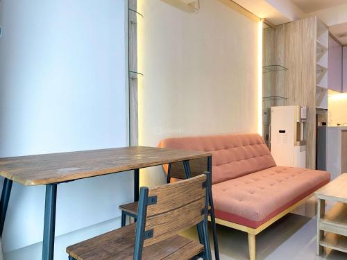 a room with a bench and a table and chairs at Good and Modern 2BR Daan Mogot City Apartment By Travelio in Jakarta