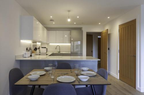 a dining room table with chairs and a kitchen at Lovely 2 Bedroom Apartment in Central Ashford in Ashford