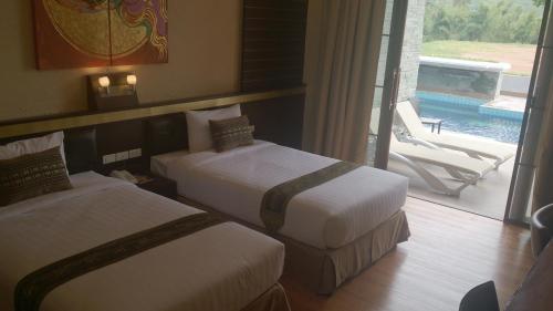 two beds in a hotel room with a view of a pool at Phurua Sanctuary Resort and Spa in Phu Rua