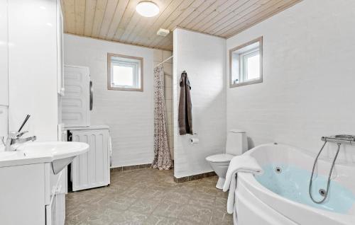a bathroom with a tub and a toilet and a sink at Nice Home In Løkken With Kitchen in Løkken