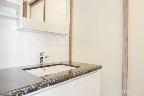 a bathroom with a sink and a mirror at Fully Furnished with Pleasure 2BR at Sky House BSD Apartment By Travelio in Tangerang