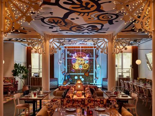 a restaurant with tables and chairs and a decorated ceiling at Mama Shelter Nice in Nice