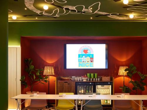 a projection screen in a restaurant with tables and chairs at Mama Shelter Nice in Nice