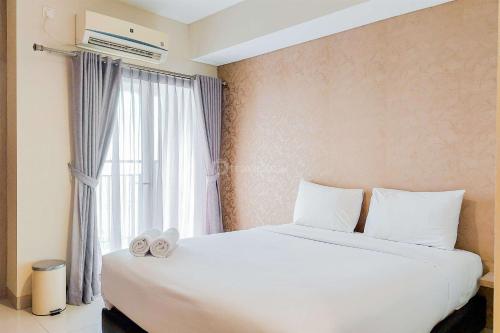 a bedroom with a large white bed and a window at Homey and Comfort Stay Studio Atria Residences Gading Serpong Apartment By Travelio in Tangerang