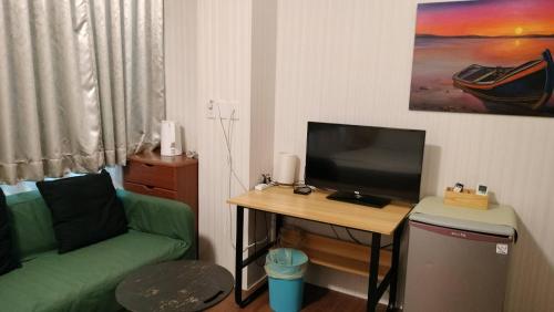 a living room with a green couch and a table with a television at 水源棧 in Fengyuan