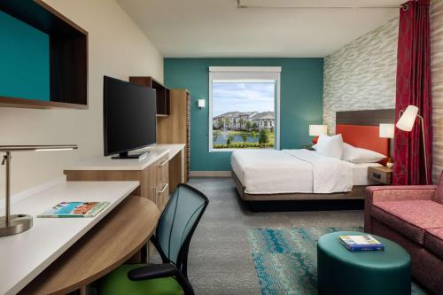 a hotel room with a bedroom with a bed and a tv at Home2 Suites By Hilton Lake Mary Orlando in Lake Mary