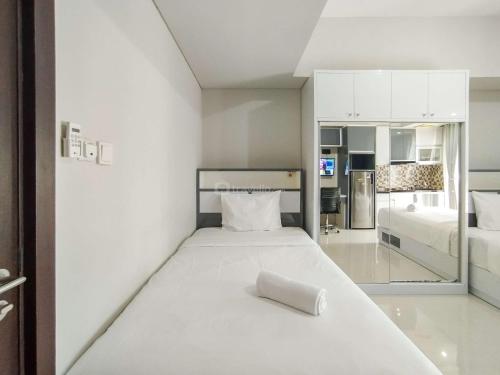 a white room with a bed and a kitchen at Strategic and Comfy Studio at Skyland City Jatinangor Apartment By Travelio in Sumedang