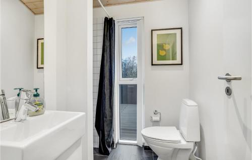a white bathroom with a toilet and a sink at Holiday Home Klitbakkevej in Lønstrup