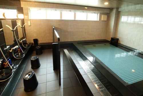 a swimming pool in a bathroom with sinks and toilets at AZ Inn Higashi Omi Notogawa Ekimae in Higashiomi
