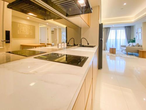 a kitchen with white counter tops and a living room at Best Deal and Strategic 2BR Marquis de Lafayette Apartment By Travelio in Semarang